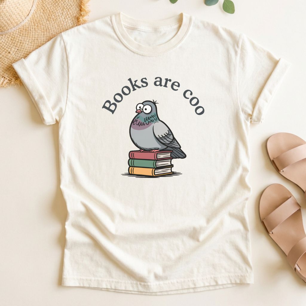 Ivory t-shirt with a graphic of a pigeon on books and text 'Books are coo' on a light background.