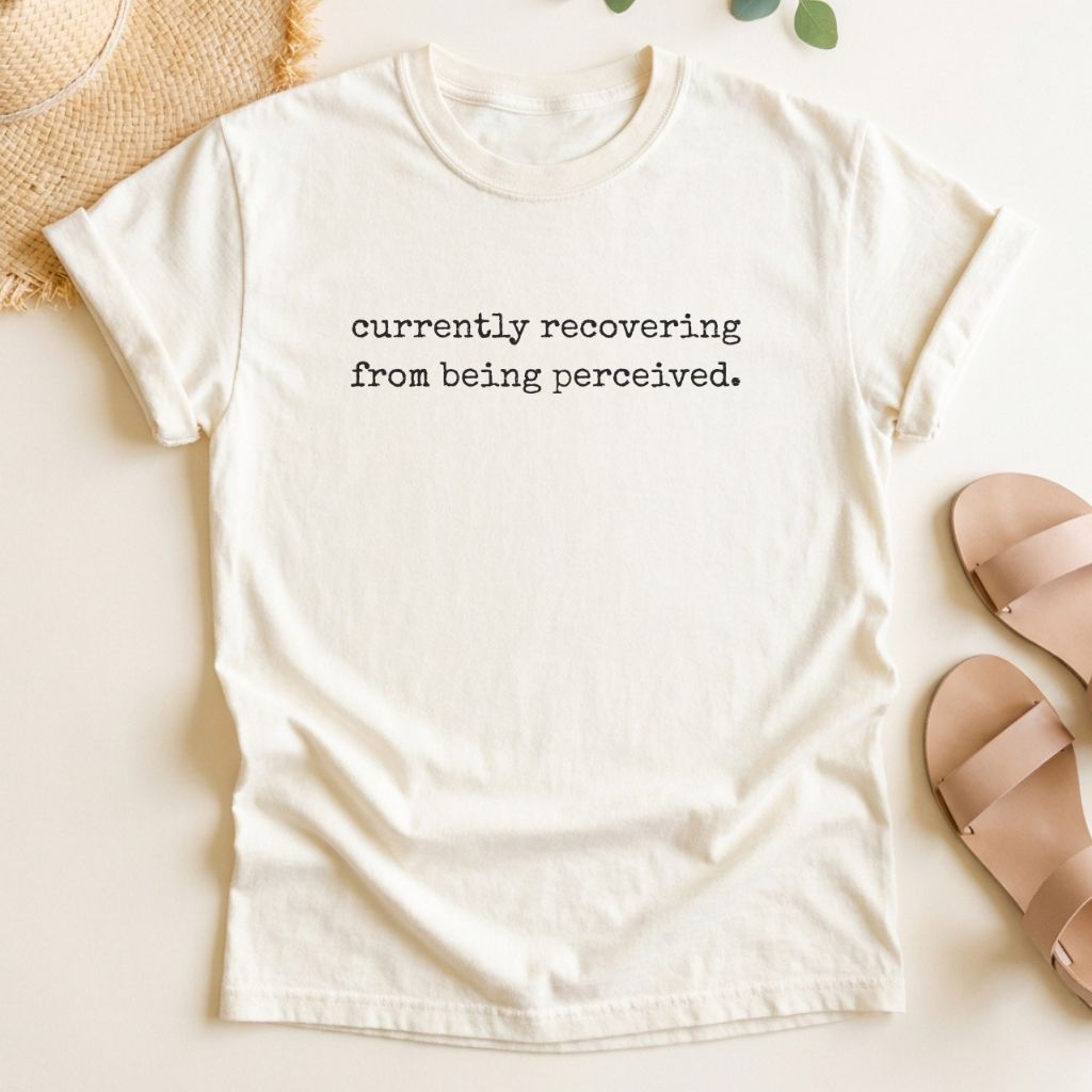 Ivory t-shirt with text 'currently recovering from being perceived' on a light background