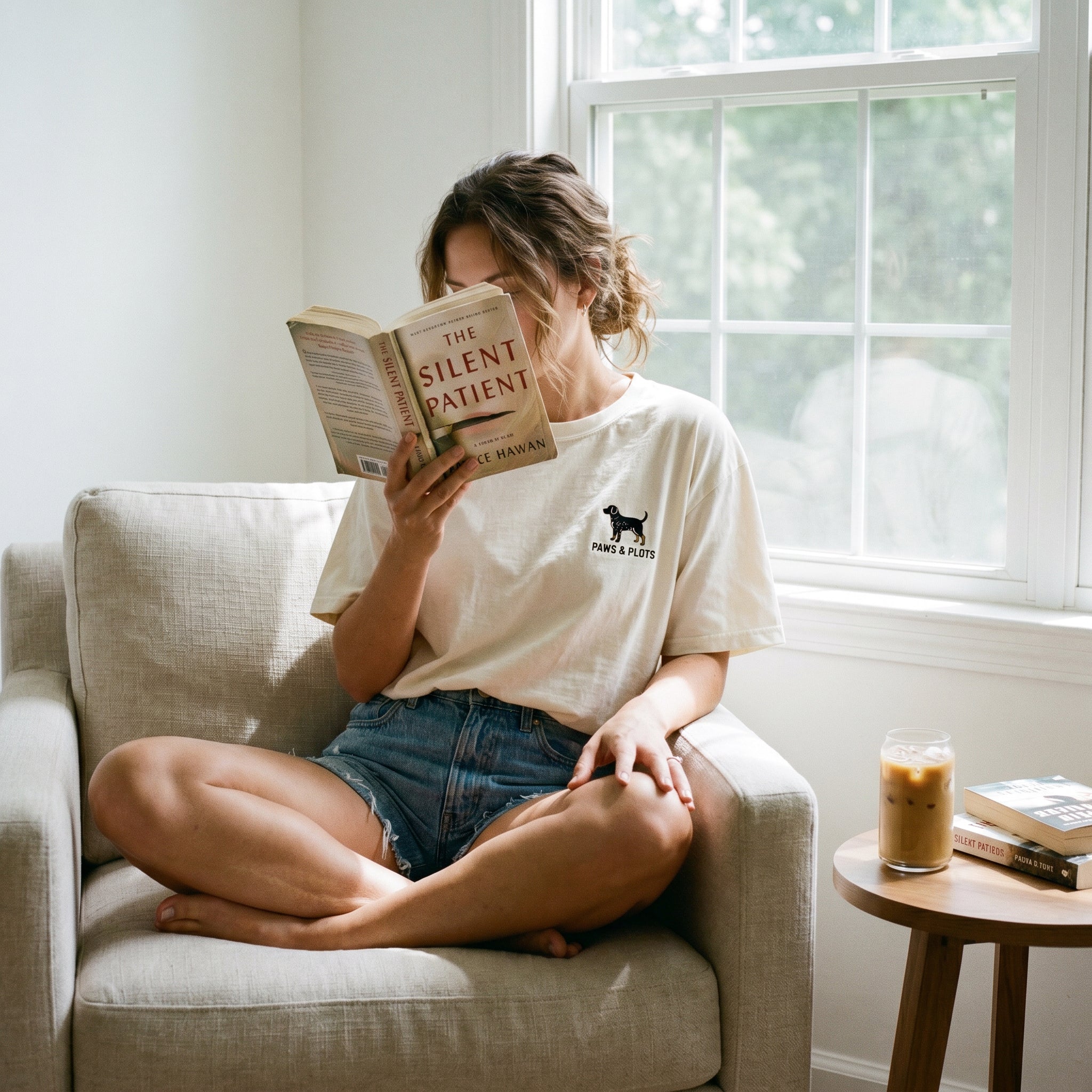 Person reading a book titled 'The Silent Patient' in a cozy living room.